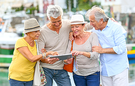 two mature couples by boats using tablet device