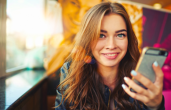 young adult woman smiling and holding mobile phone
