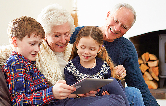 grandparents look at a tablet device with male and female grandchildren