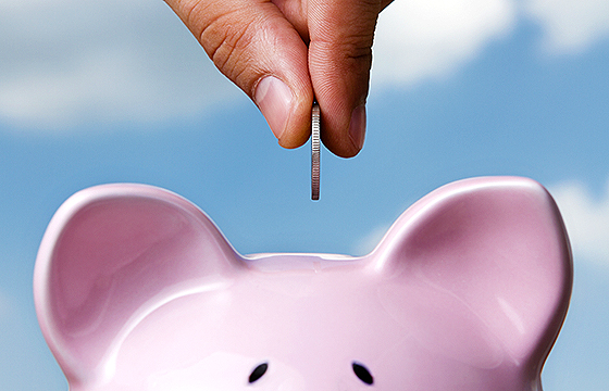 hand placing coin in piggy bank