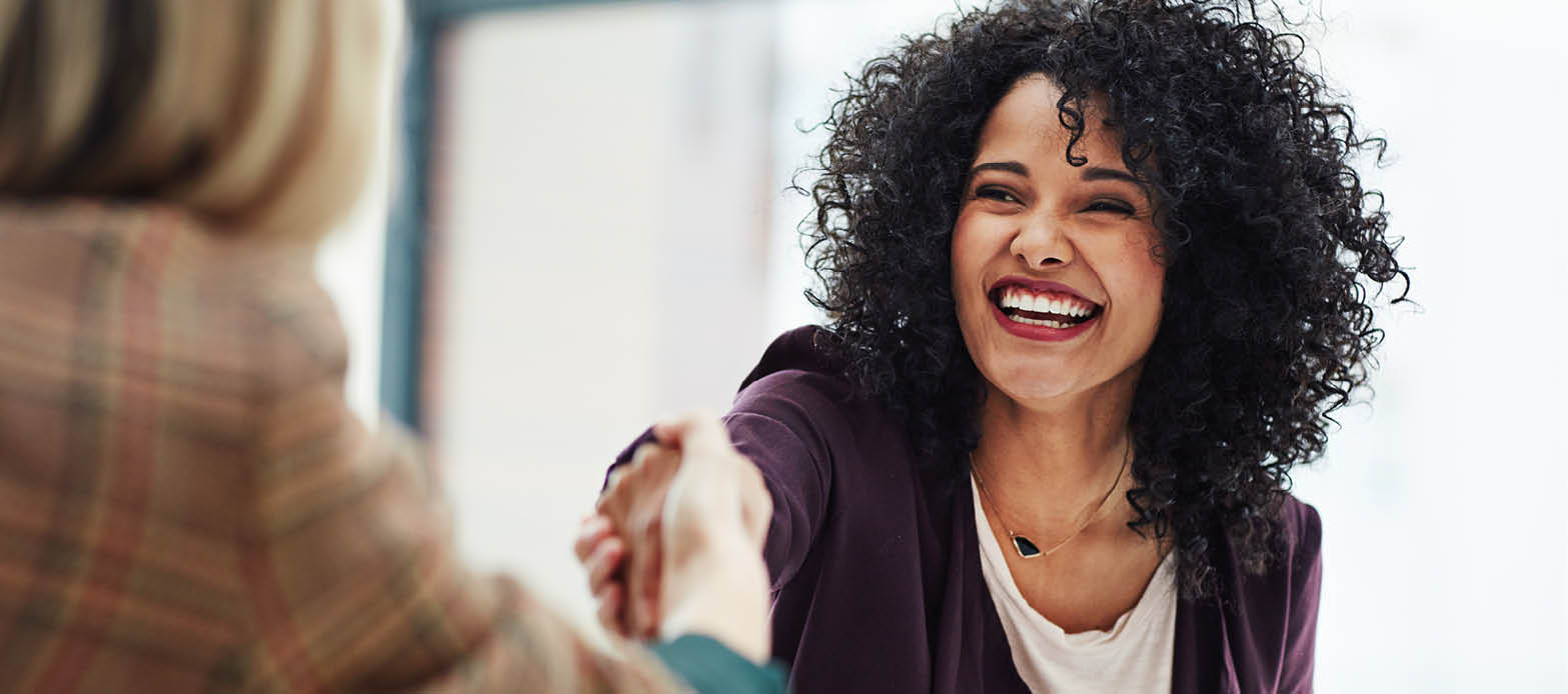 Woman smiles while shaking hands with a commercial banker