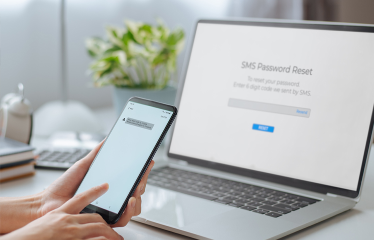 person completing two-factor authentication on phone and laptop