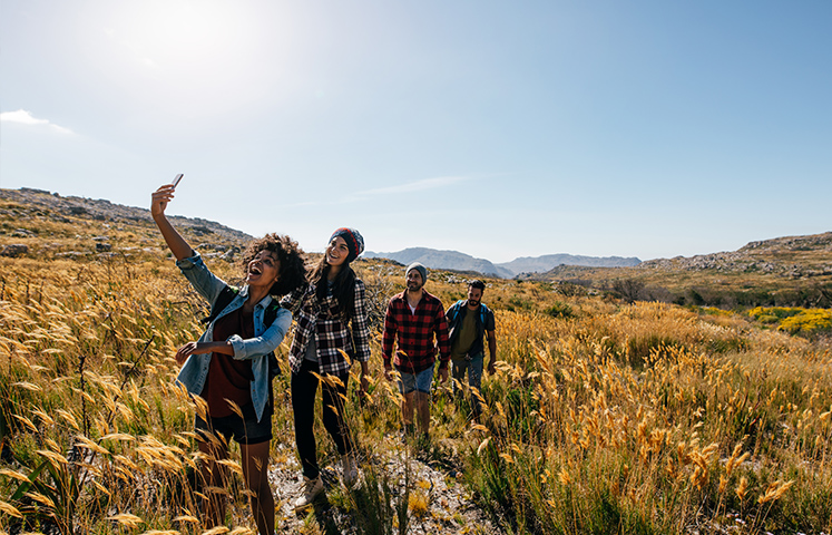 four young adults taking a selfie while hiking in a field