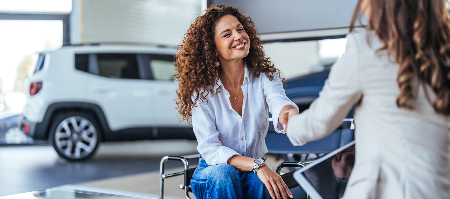 Woman shakes hands with a car saleswoman at a dealership