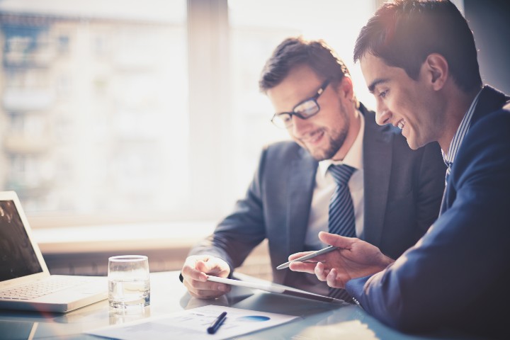 Two men review a document at work