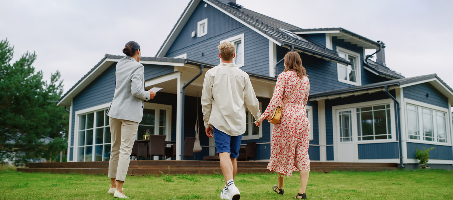 A couple and their realtor look at a house from the backyard
