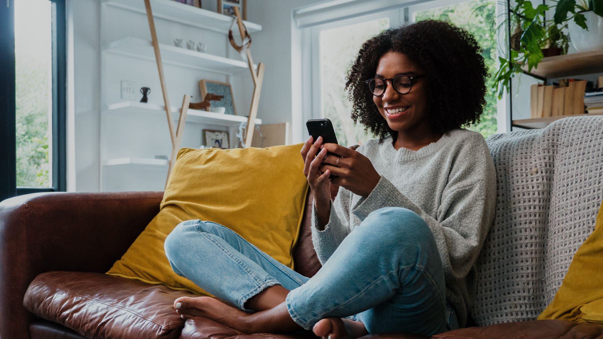 Teen smiles at phone while sitting on the couch