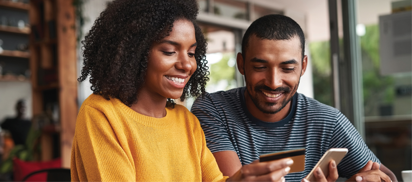 A man and a women smile while mobile banking