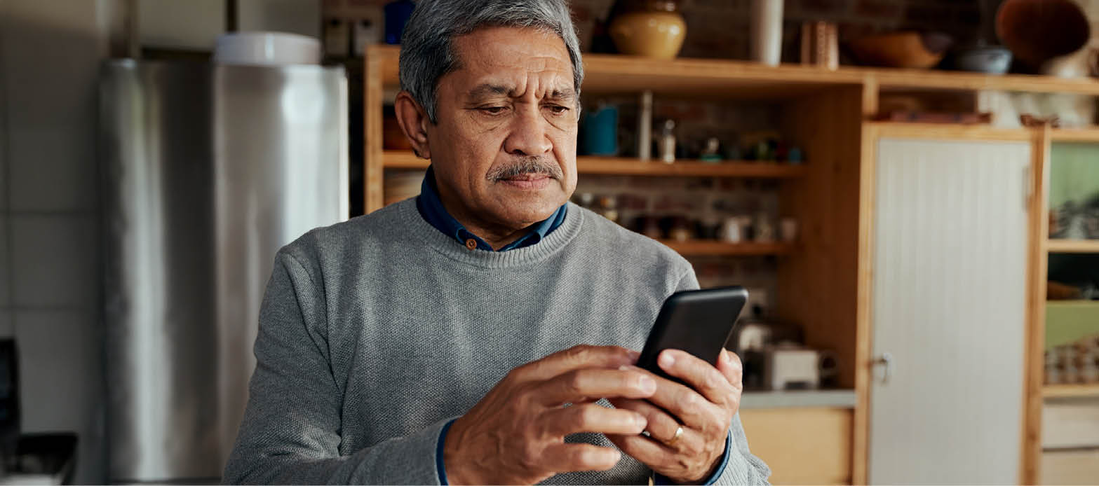 Man looks at cell phone in kitchen