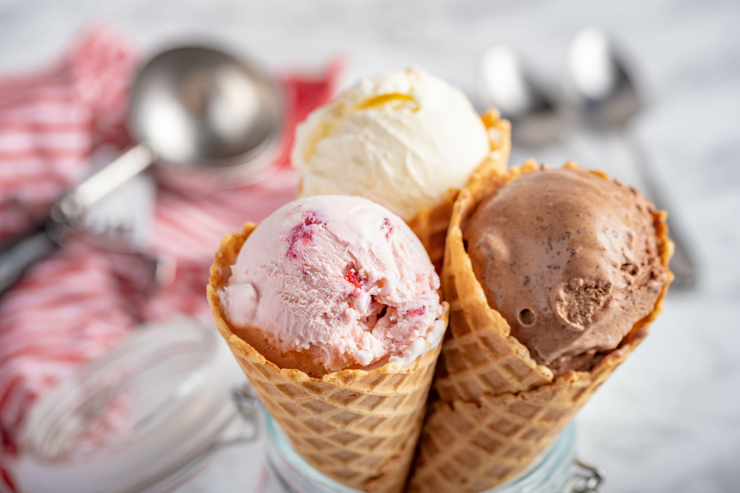 Three waffle cones with vanilla, strawberry and chocolate ice cream