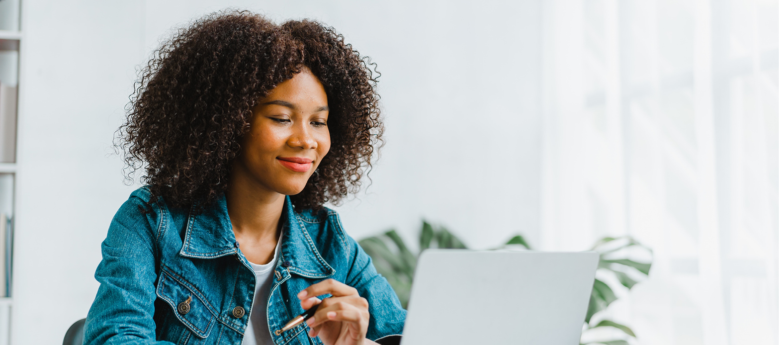 Woman sitting at table on laptop smiling.