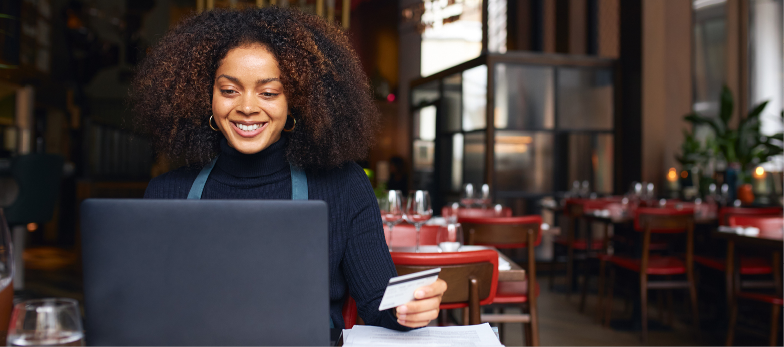 Woman looking at a computer while holding a card