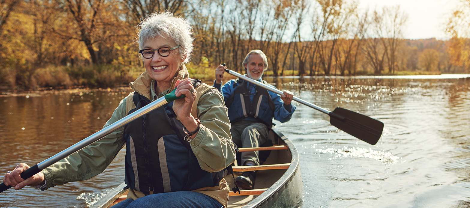 An older couple looking happy while canoeing