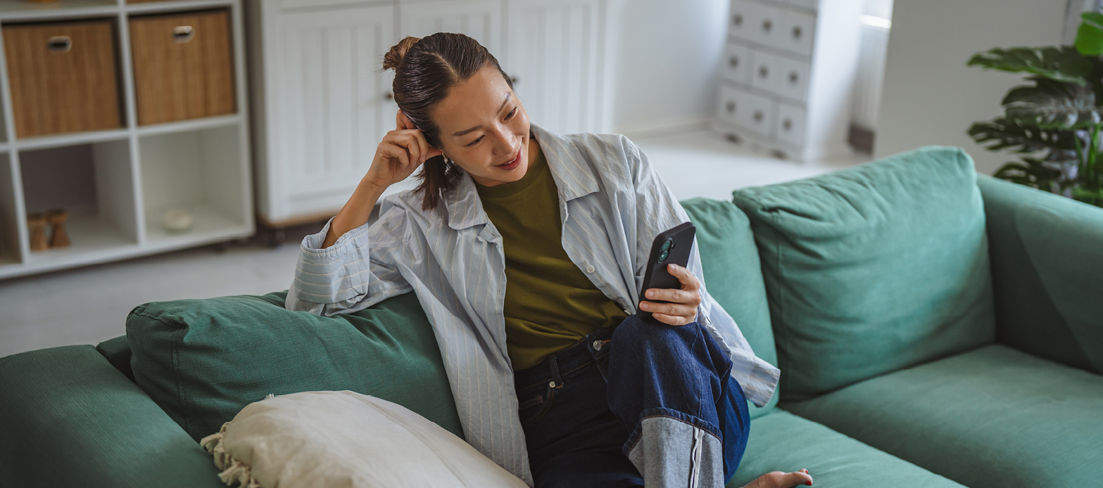 A woman sitting on the couch looking at her phone